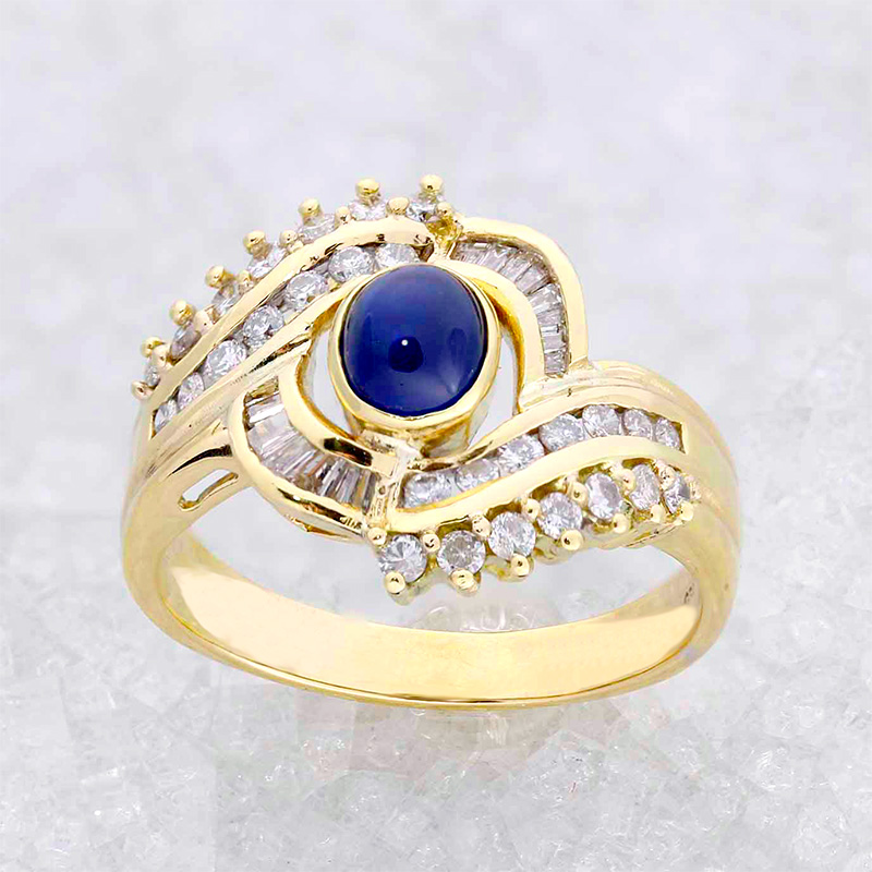 this striking ring features a central cabochon gemstone framed by two radiant layers of diamonds